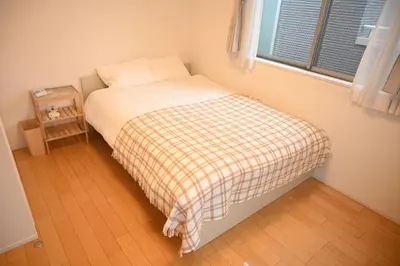 a small bedroom with a bed with a plaid blanket at Mi-Villa Pure Gray in Tokyo