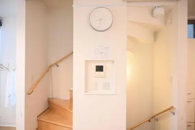 a staircase with a clock on a wall at Mi-Villa Pure Gray in Tokyo