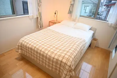 a small bedroom with a bed with a plaid blanket at Mi-Villa Pure Gray in Tokyo