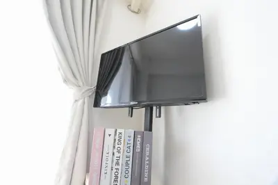 a flat screen tv hanging on a wall with books at LUANA in SHIBUYA in Tokyo