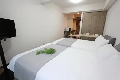 a bedroom with two beds with white sheets and a plant on it at LUANA in SHIBUYA in Tokyo