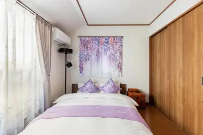 a bedroom with a large bed with purple pillows at Charming New Home Launch: Direct access to Narita & Haneda Airports, Shinjuku, and Disneyland; Close to Asakusa & Akihabara! in Tokyo