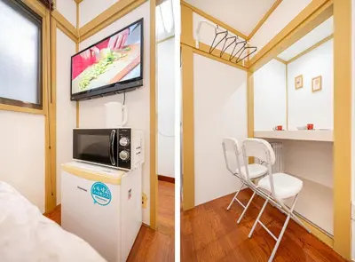 a room with a tv and a small refrigerator and a chair at Sunrise in Tokyo