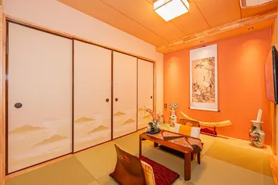a living room with orange walls and a table and chairs at KYARA Hotel\u30df\u30b9\u30df501 in Tokyo