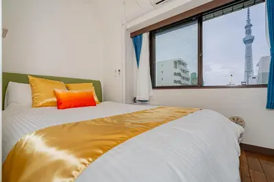 a bedroom with a bed with an orange pillow and a window at KYARA Hotel\u30df\u30b9\u30df501 in Tokyo