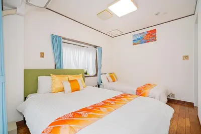 two beds in a room with white walls and orange pillows at KYARA Hotel\u30df\u30b9\u30df501 in Tokyo