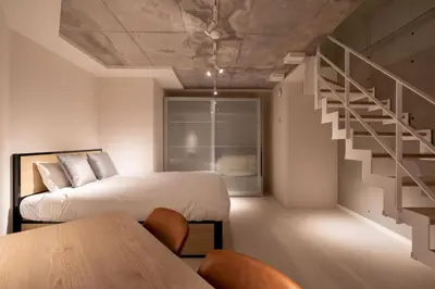 a bedroom with a bed and a staircase and a table at \u30eb\u30af\u30ec\u6771\u65b0\u5bbf in Tokyo
