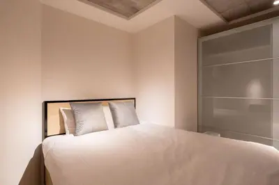 a bedroom with a bed with white sheets and pillows at \u30eb\u30af\u30ec\u6771\u65b0\u5bbf in Tokyo