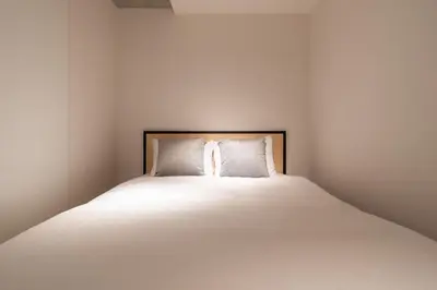 a bedroom with a large bed with white sheets at \u30eb\u30af\u30ec\u6771\u65b0\u5bbf in Tokyo