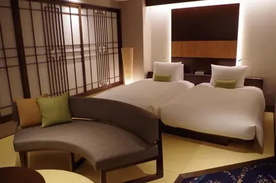 a hotel room with two beds and a chair at Hotel Ryumeikan Ochanomizu Honten in Tokyo