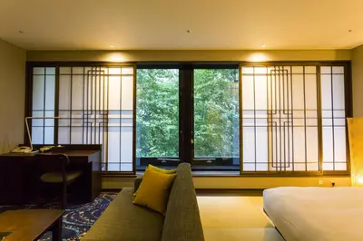 a bedroom with a bed and a desk and windows at Hotel Ryumeikan Ochanomizu Honten in Tokyo