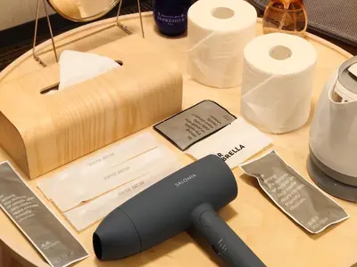 a black remote control on a table with rolls of paper at Oda hotel Akihabara in Tokyo