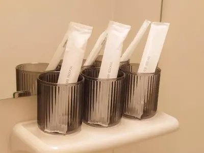 four metal cups sitting on top of a toothbrush holder at Oda hotel Akihabara in Tokyo