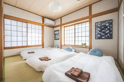 two twin beds in a room with windows at Japandi House Haneda in Tokyo