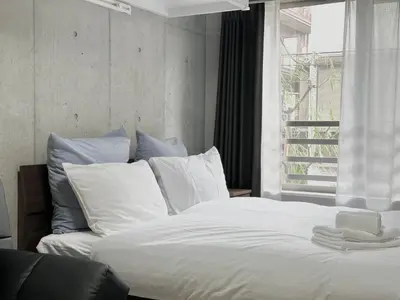 a bed with white sheets and pillows next to a window at Hotel \u30de\u30fc\u30d9\u30e9\u30b9Asakusa #1 in Tokyo