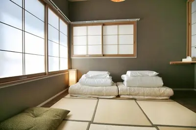 two beds in a room with windows at QU102 Edogawa Japanese Style Apartment 102 has direct access to Akihabara and Shinjuku, with convenient transportation and free WiFi in Tokyo