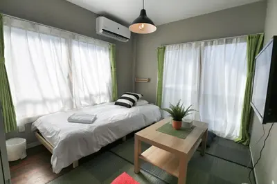 a bedroom with a bed and a table and windows at QU202 Edogawa Japanese Style Apartment 202 has direct access to Akihabara and Shinjuku, with convenient transportation and free WiFi in Tokyo