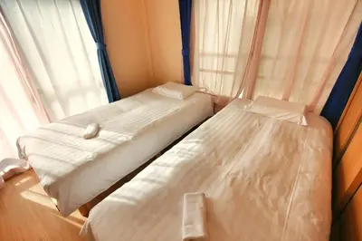 two beds sitting next to a window in a bedroom at QU301 Edogawa Japanese Style Apartment 301 has direct access to Akihabara and Shinjuku, with convenient transportation and free WiFi in Tokyo