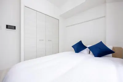 a bedroom with a white bed with blue pillows at \u30d7\u30ec\u30fc\u30eb\u30c9\u30a5\u30fc\u30af\u5927\u68ee\u753a ll in Tokyo