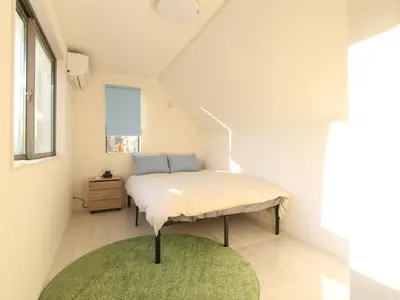 a bedroom with a bed with a green rug at New building Shinjuku area town house in Tokyo