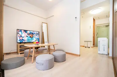 a living room with a table and stools and a tv at Ikebukuro East Exit, 2BR in Tokyo