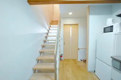 a staircase in a house with white walls and wooden floors at Shinjuku 'Deep Lane' Villa in Tokyo