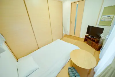 a small room with a bed and a table and a tv at Shinjuku 'Deep Lane' Villa in Tokyo