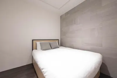 a bedroom with a white bed and a wall at Lega land\u5e61\u30f6\u8c37 in Tokyo