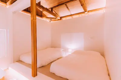 two beds in a room with white walls at One Harajuku: Private Oasis in Tokyo
