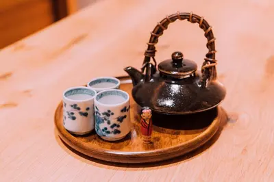 a tea pot and three cups on a wooden tray at One Harajuku: Private Oasis in Tokyo