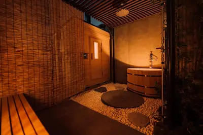 a bathroom with a tub and a sink and a bench at One Harajuku: Private Oasis in Tokyo