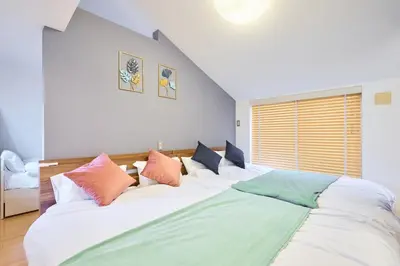 a bedroom with a large white bed with colorful pillows at \u5e83\u3005130\u5e73\u7c73 \u6700\u592713\u540d \u99c5\u5f92\u6b694\u5206 10Gwifi \u591c\u306e\u30d1\u30fc\u30c6\u30a3\u30fc\u3068\u98f2\u307f\u4f1a\u7981\u6b62 in Tokyo