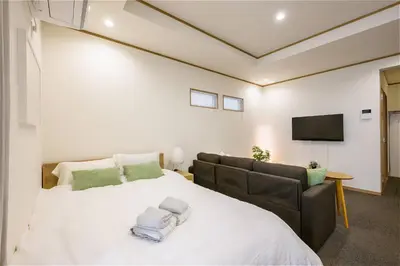 a bedroom with a large white bed and a couch at Komei Hotel/5min to station/Direct access to Narita and Haneda/Asakusa/Sky tree in Tokyo