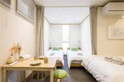 a room with two beds and a table in it at Komei Hotel/5min to station/Direct access to Narita and Haneda/Asakusa/Sky tree in Tokyo