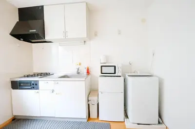 a small kitchen with white cabinets and a microwave at takadababa 4 mins walk/新宿圈! 高速无限制网路/车站步行4分钟新装修公寓102 in Tokyo