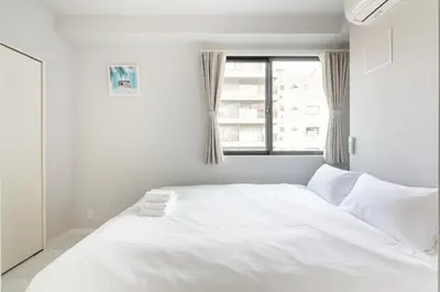 a white bed in a room with a window at SOLASIA residence \u5317\u4e0a\u91ce in Tokyo