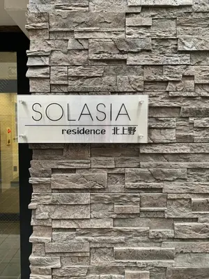 a sign on the side of a stone wall at SOLASIA residence \u5317\u4e0a\u91ce in Tokyo