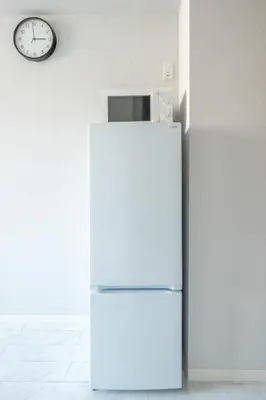 a white refrigerator in a kitchen with a clock at SOLASIA residence \u5317\u4e0a\u91ce in Tokyo
