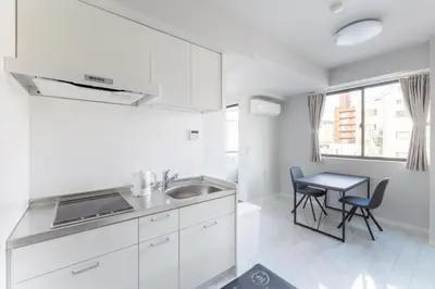 a white kitchen with a sink and a table at SOLASIA residence \u5317\u4e0a\u91ce in Tokyo