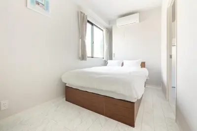 a bedroom with a bed with white sheets and a window at SOLASIA residence \u5317\u4e0a\u91ce in Tokyo