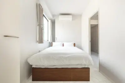 a bedroom with a bed with white sheets and a window at SOLASIA residence \u5317\u4e0a\u91ce in Tokyo