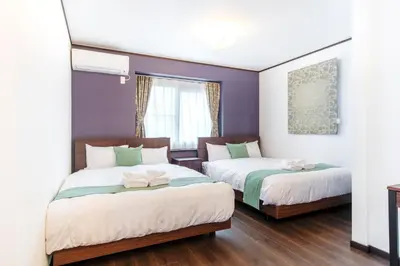two beds in a room with purple walls and wooden floors at Family Stay Tokyo Hikifune in Tokyo