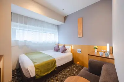 a hotel room with a bed and a chair at Hotel Gracery Shinjuku in Tokyo
