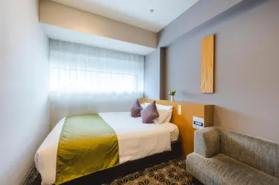 a bedroom with a bed and a chair and a couch at Hotel Gracery Shinjuku in Tokyo