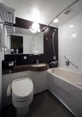 a bathroom with a toilet and a sink and a tub at Hotel Coco Grand Kitasenju in Tokyo