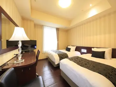 a hotel room with two beds and a desk at Hotel Coco Grand Kitasenju in Tokyo
