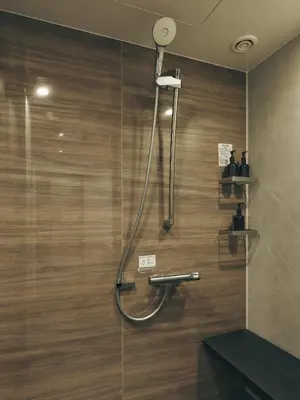 a shower in a bathroom with a wooden wall at illi Mani Shibuya in Tokyo