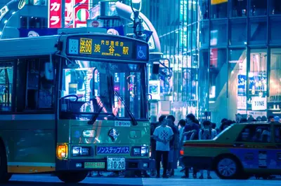 a bus driving down a busy city street at night at illi Mani Shibuya in Tokyo