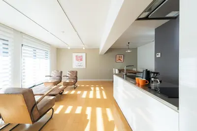 a living room with chairs and a kitchen with a counter at Courtyard HIROO in Tokyo