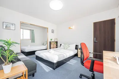 a hotel room with two beds and a desk at Fukuei Stay Tokyo in Tokyo